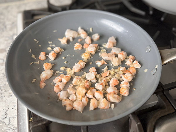 Shrimp and garlic sautéing in a skillet.