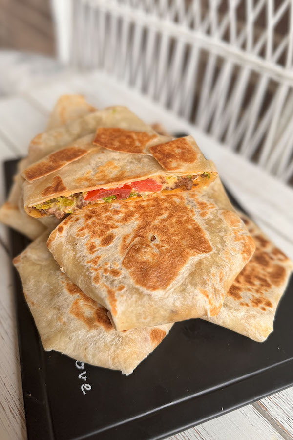 A pile of toasted tortilla wraps with one wrap halved to expose the filling.