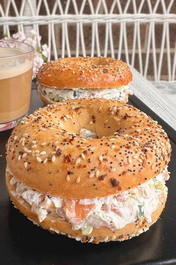 Breakfast Bagel Sandwiches with Salmon and Cream Cheese with a cup of coffee in the background.