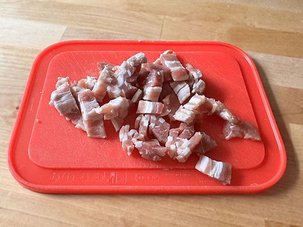 Chopped raw bacon on a cutting board.