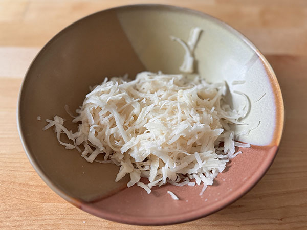 Grated raw potato in a bowl.