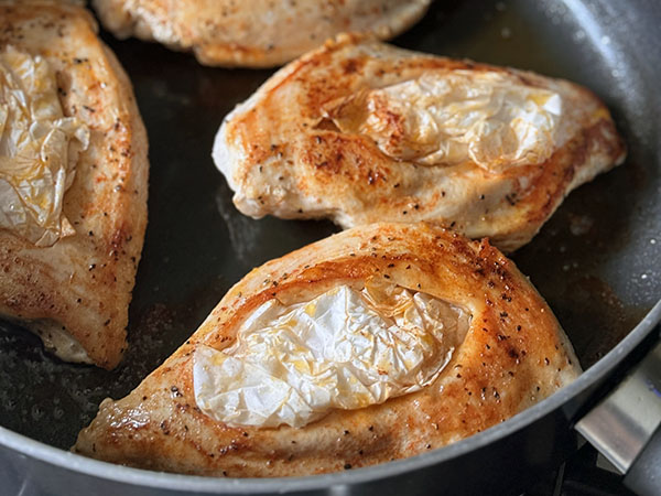 Перевернутые куриные грудки жарятся на сковороде кармашками вверх.
