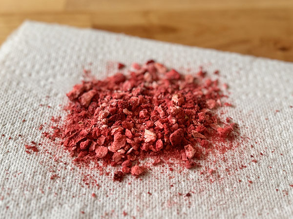 Broken freeze-dried strawberries on a paper towel.