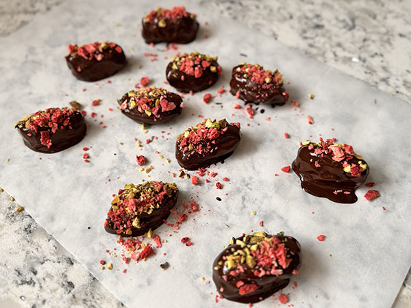 Chocolate covered, almond butter stuffed dates sprinkled with pistachios and strawberries.