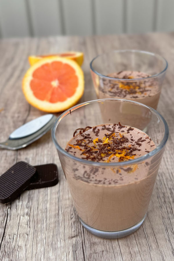 Chocolate Orange Protein Mousse with Cottage Cheese garnished with orange zest and chocolate shavings, and a halved orange on the side.