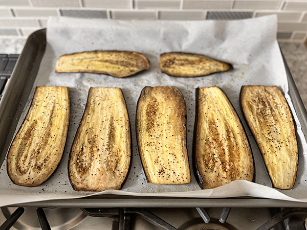 Baked eggplant slices on a baking sheet straight from the oven.