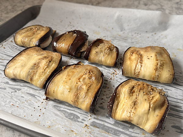 Baked eggplant slices folded in half with mozzarella-tomato filling inside.