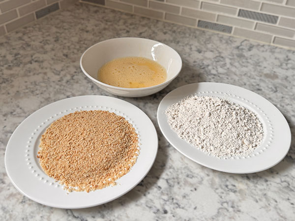 Breading station with 3 plates: flour, egg mixture and bread crumbs.