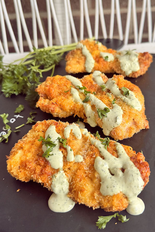 Crusty Air fryer Panko chicken thighs topped with sour cream parsley sauce.
