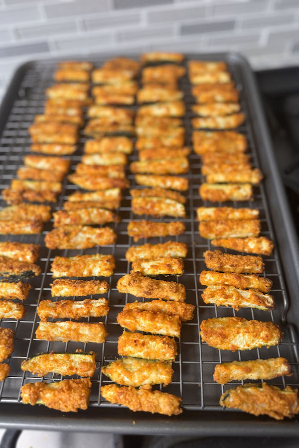 Baked, golden brown and crispy zucchini sticks on a baking rack.