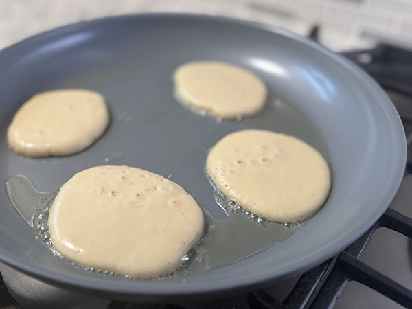 Dairy-free pancakes cooking in a frying pan.