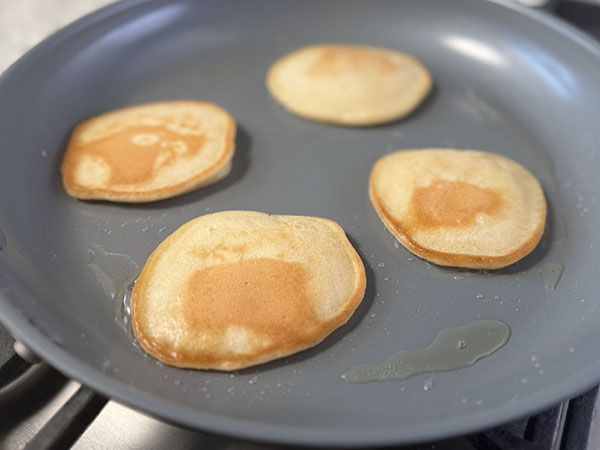 Golden-brown milk-free pancakes in a skillet finishing cooking.