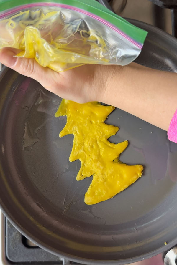 Drawing a Christmas tree on a skillet using egg yolks in a ziploc bag.
