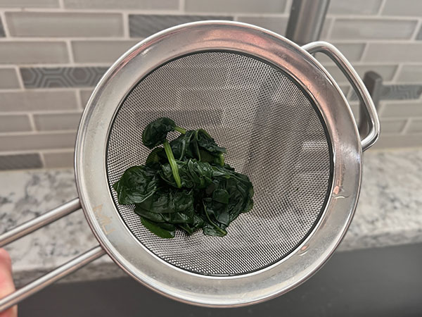 Draining spinach to get it ready to blend with water to make green coloring.
