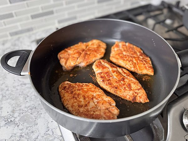Golden brown fried chicken breasts in a skillet.
