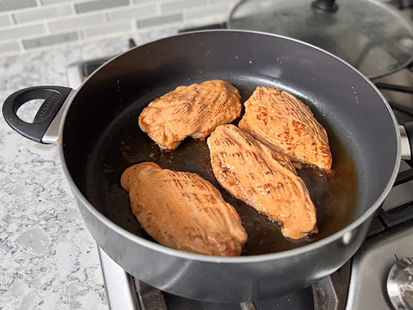 Обжаренные на сковороде куриные грудки, покрытые соусом.