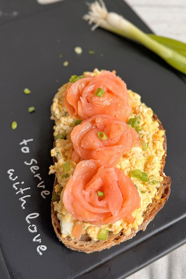 Smoked Salmon & Egg Salad Sandwich with Green Onions on a serving board.
