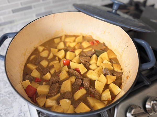 Potatoes added to beef curry stew for cooking.