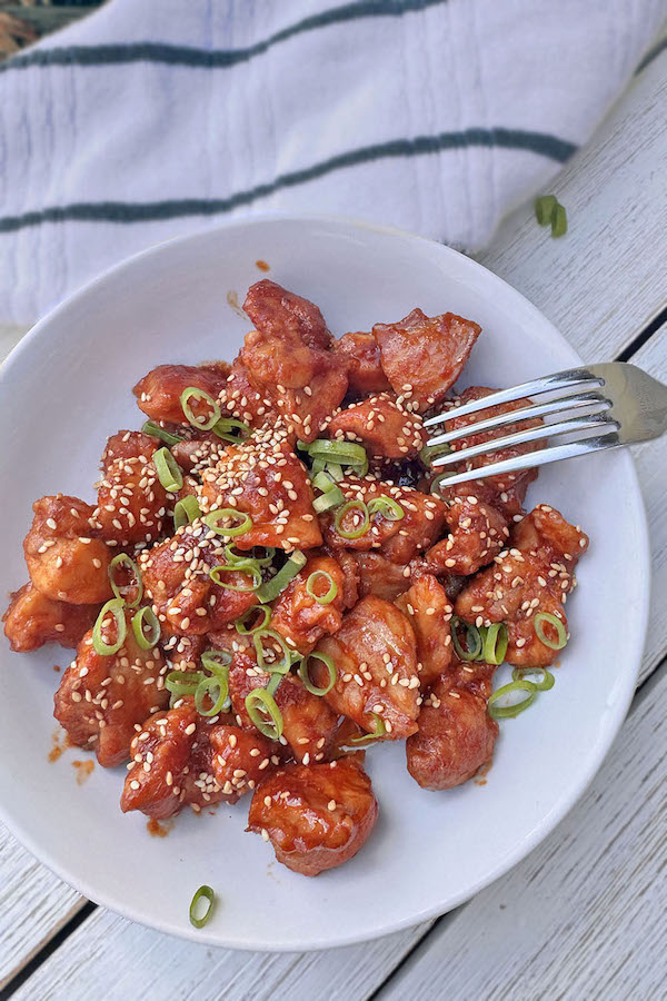 Spicy Korean Garlic Chicken sprinkled with sesame seeds and chopped scallions in a bowl.