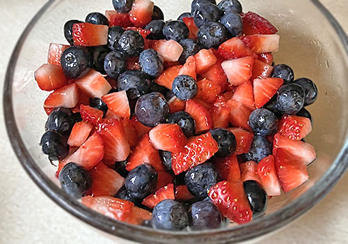 Mix of blueberries and chopped strawberries sweetened with maple syrup for pancake topping.