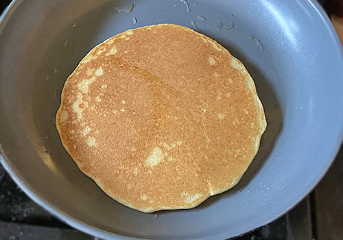 Cooking the other side of the pancake until golden brown.