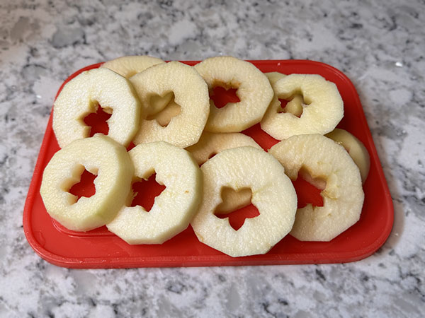 Apple sliced into rings on a cutting board.