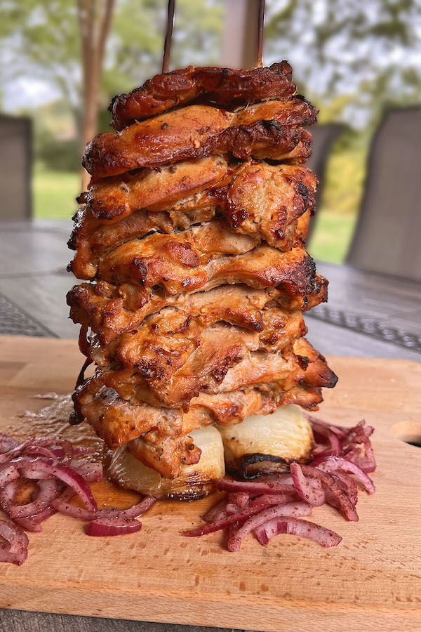 Juicy oven roasted chicken shawarma tower with marinated red onions on the sides.
