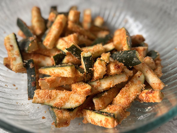 Zucchini sticks coated with flour and seasonings: paprika, garlic powder, onion powder, and salt.
