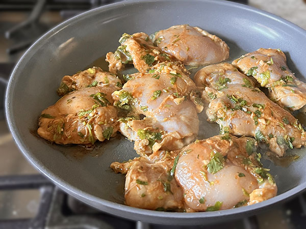 Marinated Mexican spiced chicken thighs cooking in a skillet.