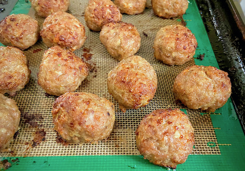 Oven baked Swedish meatballs on a baking sheet lined with a silicone mat