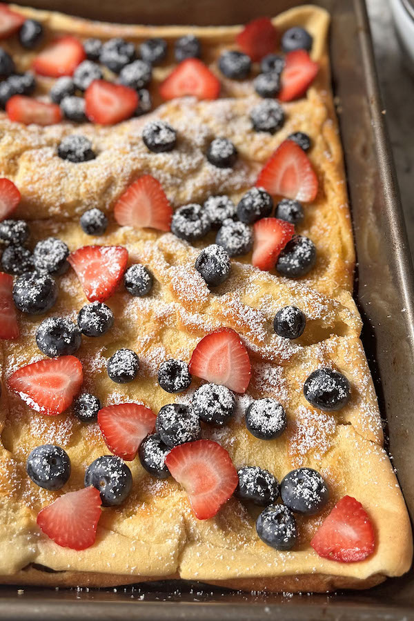 Dutch Baby Pancake topped with fresh blueberries, sliced strawberries and confectioners sugar.