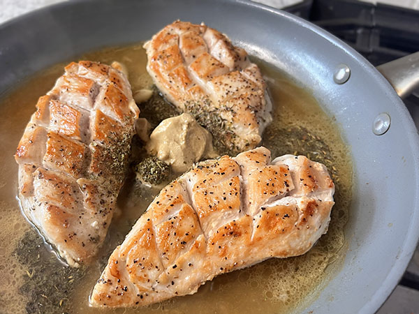 Pan-seared chicken pieces with sauce ingredients: mustard, chicken broth and lemon juice.